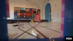 Mlada posetiteljka izložbe "Grad od kockica" igra se Lego kockicama u Nacionalnom muzeju građevinarstva u Vašingtonu. (Foto: VOA/Screenshot)