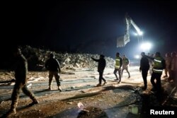 People walk outside next to a building that collapsed after an earthquake in Antakya in Hatay province, Turkey, Feb. 20, 2023.