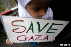 A child holds a "SAVE GAZA" sign during a pro-Palestinian rally in front of the Israeli Embassy in Bangkok, Oct. 21, 2023.