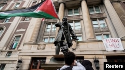 A student protester parades a Palestinian flag outside the entrance to Hamilton Hall on the campus of Columbia University in New York, April 30, 2024. (Mary Altaffer/Pool via Reuters)