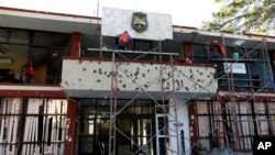 FILE - Workers repair the entrance of City Hall riddled with bullet holes in Villa Union, Mexico, Dec. 2, 2019, after 22 people were killed in a weekend gun battle between a drug cartel and security forces.