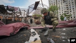 A sapper inspects fragments of a Russian air bomb that hit a living area in Kharkiv, Ukraine, May 22, 2024.