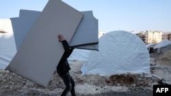 FILE - People receive mattresses distributed by an NGO, at a makeshift camp in the city of Afrin in the rebel-held part of Aleppo province, Syria, Feb. 16, 2023.