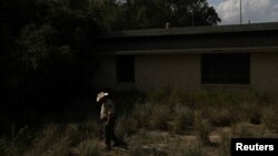 FILE - Brooks County Sheriff's Deputy Elias Pompa searches for illegal migrants at an abandoned elementary school in Encino, Texas, Aug. 14, 2018.
