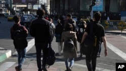 FILE - A group of young Iranian women cross a street without wearing their mandatory Islamic headscarves in Tehran, Iran, Nov. 14, 2022.