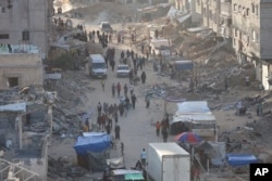 Palestinians walk through the debris after an Israeli air and ground offensive in Khan Younis, southern Gaza Strip, May 15, 2024.