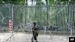 A Polish soldier patrols the metal barrier border with Belarus, in Bialowieza Forest, on May 29, 2024. Poland says Belarus and its main supporter Russia are behind a surging push by migrants in Belarus toward the European Union. 