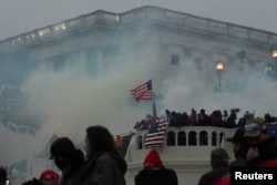 FILE - Police clear the U.S. Capitol Building with tear gas as supporters of President Donald Trump gather outside in Washington on Jan. 6, 2021.