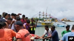 In this photo provided by the Philippine Coast Guard, rescuers carry the body of one of the victims as it arrives at a port in Infanta, Pangasinan province, Philippines, Oct. 3, 2023.(Philippine Coast Guard via AP)