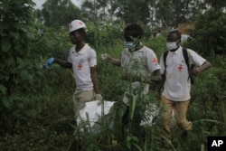 FILE - Red Cross volunteers carry the body of a civilian who was killed in the DRC village of Mukondi, on March 9, 2023. At least 36 people were killed when the Allied Democratic Forces attacked the village and burned residents' huts.