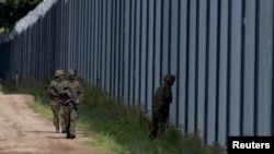 FILE - Polish soldiers patrol along a border fence on the Polish-Belarusian border, in Usnarz Gorny, Poland, Aug. 30, 2023.