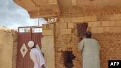 People check a damaged house as smoke billows in southern Khartoum, Sudan, on June 12, 2023.