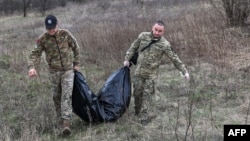 Members of a Ukrainian Civil-Military Cooperation team carry the remains of a Russian soldier in the village of Synykha, in Ukraine's Kharkiv region, April 8, 2023.