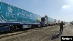 An Egyptian volunteer walks next to trucks carrying humanitarian aid from Egyptian NGOs for Palestinians, as they await for the reopening of the Rafah crossing at the Egyptian side to enter Gaza, in Rafah, Egypt, Oct. 19, 2023.