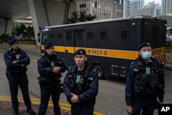 Police officers stand guard as an armored prison van carrying activist publisher Jimmy Lai leaves West Kowloon Magistrates' Courts, in Hong Kong, Dec. 18, 2023.