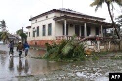This handout photograph taken and distributed by UNICEF on March 12, 2023, shows people walking along a street damaged by the impact of Cyclone Freddy in the city of Quelimane.