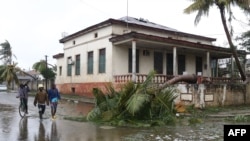 This handout photograph taken and distributed by UNICEF on March 12, 2023, shows people walking along a street damaged by the impact of Cyclone Freddy in the city of Quelimane.