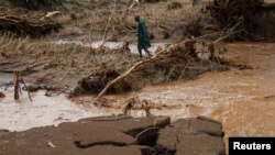 কেনিয়াতে ভারী বৃষ্টিপাতের ফলে আকস্মিক বন্যায় বেশ কয়েকটি বাড়ি নিশ্চিহ্ন হয়ে যাওয়ার পর জাতীয় যুব পরিষেবার একজন সদস্য নিখোঁজদের সন্ধান করছেন। ১মে, ২০২৪।