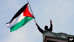 A protester waves a Palestinian flag above Hamilton Hall on the campus of Columbia University in New York, April 30, 2024.
