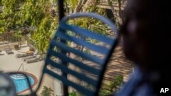 A person soaks in the sun at a pool of a nearby hotel while Charles Nahale shares his fears of displacement on Oct. 10, 2023, in Lahaina, Hawaii.