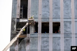 Workers clean a part of a damaged skyscraper in the 'Moscow City' business district after a reported drone attack in Moscow, Aug. 23, 2023.