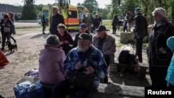 Residents of Vovchansk and nearby villages wait for buses amid an evacuation to Kharkiv due to Russian shelling, near the town of Vovchansk, in Ukraine's Kharkiv region, May 10, 2024.