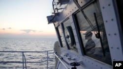 FILE - A member of the Philippine Coast Guard watches from the bridge of the BRP Malabrigo as they patrol and resupply troops at Philippine-occupied areas in the South China Sea, Apr. 19, 2023.