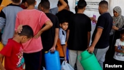 Palestinians gather to collect water, amid shortages of drinking water, as the Israeli-Palestinian conflict continues, in Khan Younis in the southern Gaza Strip, Oct. 15, 2023.