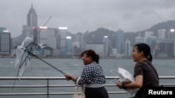 A woman holds a broken umbrella as Super Typhoon Saola approaches, in Hong Kong, China, Sept.1, 2023. 