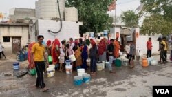 As taps in their homes run dry during the summer, people fill water for their daily use from an overhead tank. (Anjana Pasricha/VOA)
