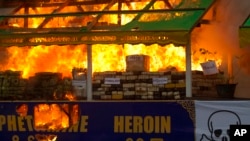 FILE - Smoke and flames billow from burning narcotic drugs during a destruction ceremony of seized drugs on the outskirts of Yangon, Myanmar, on June 26, 2018. Myanmar is the hub of the region's billion-dollar drug trade.