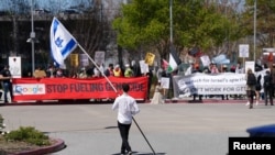 A counter-protester holding an Israeli flag walks into the parking lot near a protest at Google Cloud offices in Sunnyvale, California, April 16, 2024.