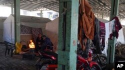 FILE - Syrian refugees warm themselves with fire in front of tents were set in a public market space as shelter in Islahiye District of Gaziantep, southern Turkey, Feb. 11, 2023.