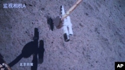 In this photo released by Xinhua News Agency, a replay screen shows Chang'e-6 probe collecting samples on the moon surface, at Beijing Aerospace Control Center (BACC) in Beijing, June 4, 2024.