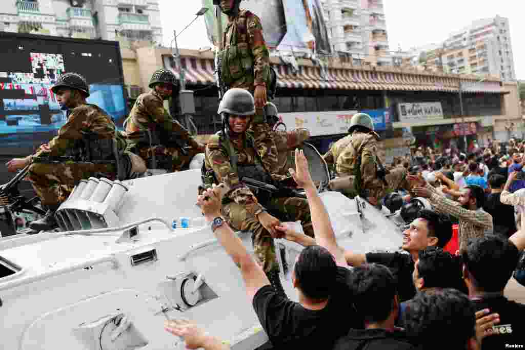 People shake hands with army personnel as they celebrate the resignation of Bangladeshi Prime Minister Sheikh Hasina in Dhaka, August 5, 2024.