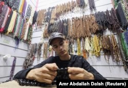 Sameh Saied sedang membetulkan tasbih di tokonya di pasar Khan el-Khalili saat Ramadan, di distrik al-Hussein, Kairo, Mesir, 23 Maret 2024. (Foto: Amr Abdallah Dalsh/Reuters)