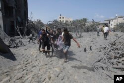 Palestinians evacuate a dead person from a site hit by an Israeli bombardment on Khan Younis, southern Gaza Strip, July 13, 2024.