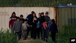 FILE - Migrants walk past a barrier after they crossed the Rio Grande and entered the US from Mexico, Oct. 19, 2023, in Eagle Pass, Texas.