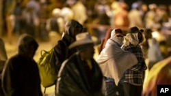 Migrants wait in the cold at a gate in the border fence after crossing from Ciudad Juarez, Mexico, into El Paso, Texas, in the early hours of May 11, 2023.