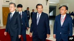 FILE - Cambodia's Prime Minister Hun Sen, center, walks together with South Korea President Moon Jae-in, left, as Cambodian tycoon Kith Meng, right, accompanies them before a business forum at the Peace Palace, in Phnom Penh, Cambodia, March 15, 2019. 