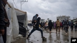 Palestinians displaced by the Israeli air and ground offensive on the Gaza Strip walk through a makeshift tent camp in Rafah on Jan. 27, 2024.