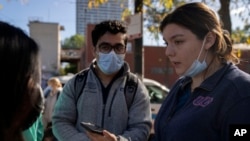 FILE - UIC med student Sara izquierdo, right, speaks to other members of the Mobile Migrant Health Team outside of the 1st District police station where migrants are camped, Oct. 7, 2023, in Chicago.