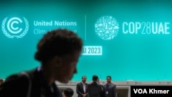 Participants walk through a screen broadcast of the opening ceremony of the United Nations Climate Change Summit, or COP28 In Dubai, United Arab Emirates on December 1, 2023. (Kann Vicheika/VOA Khmer)