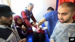 Palestinian medics treat a girl wounded in the Israeli bombardment at a building of an UNRWA vocational training center which displaced people use as a shelter in Khan Younis, southern Gaza Strip, Jan. 24, 2024.