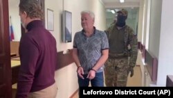 Robert Shonov, mantan pegawai konsulat AS di Vladivostok, berjalan diantar petugas menuju ruang sidang Pengadilan Negeri Lefortovo di Moskow, Rusia, Kamis, 18 Mei 2023. Rusia menuduh ia sebagai mata-mata. (Foto: via AP)