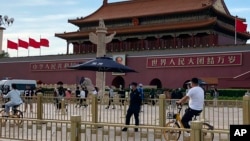 A security person watch over residents passing in front of Tiananmen Gate in Beijing, June 4, 2023.