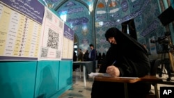 A voter fills out her ballot in the parliamentary and assembly of experts elections at a polling station in Tehran, Iran, March 1, 2024.