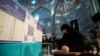 Seorang perempuan mengenakan hijab sedang mengisi surat suara di tempat pemungutan suara di Tehran, Iran, 1 Maret 2024. (Foto: Vahid Salemi/AP Photo)