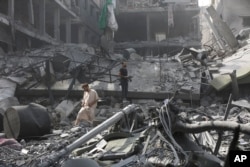Palestinians inspect the damage of destroyed buildings following Israeli airstrikes on Gaza City, Oct. 23, 2023.