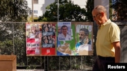 FILE - A man walks past electoral posters ahead of the July 23 snap election, in Ronda, Spain, July 7, 2023. 